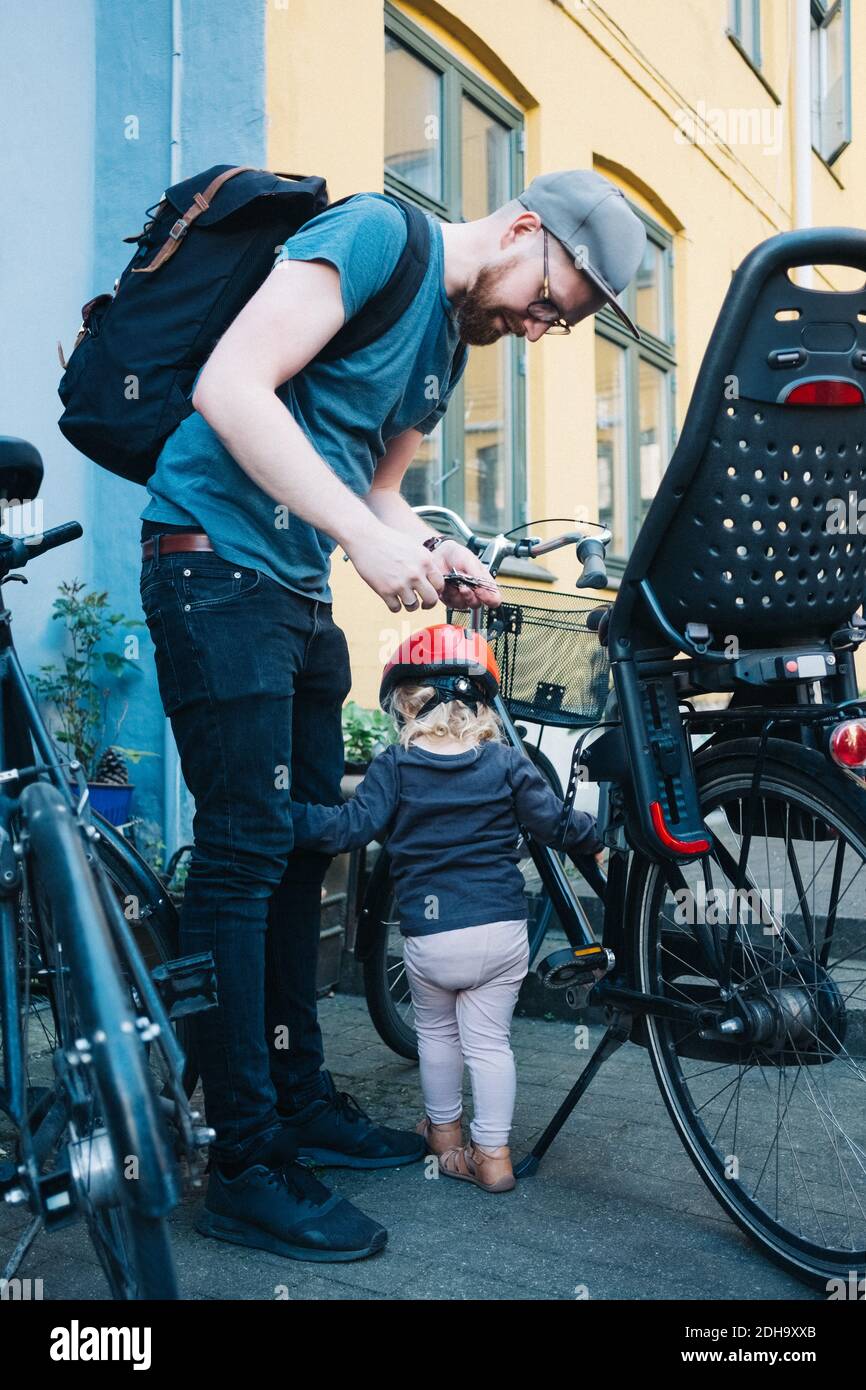 Tutta la lunghezza del padre e della figlia che si levano in piedi in bicicletta sopra via Foto Stock