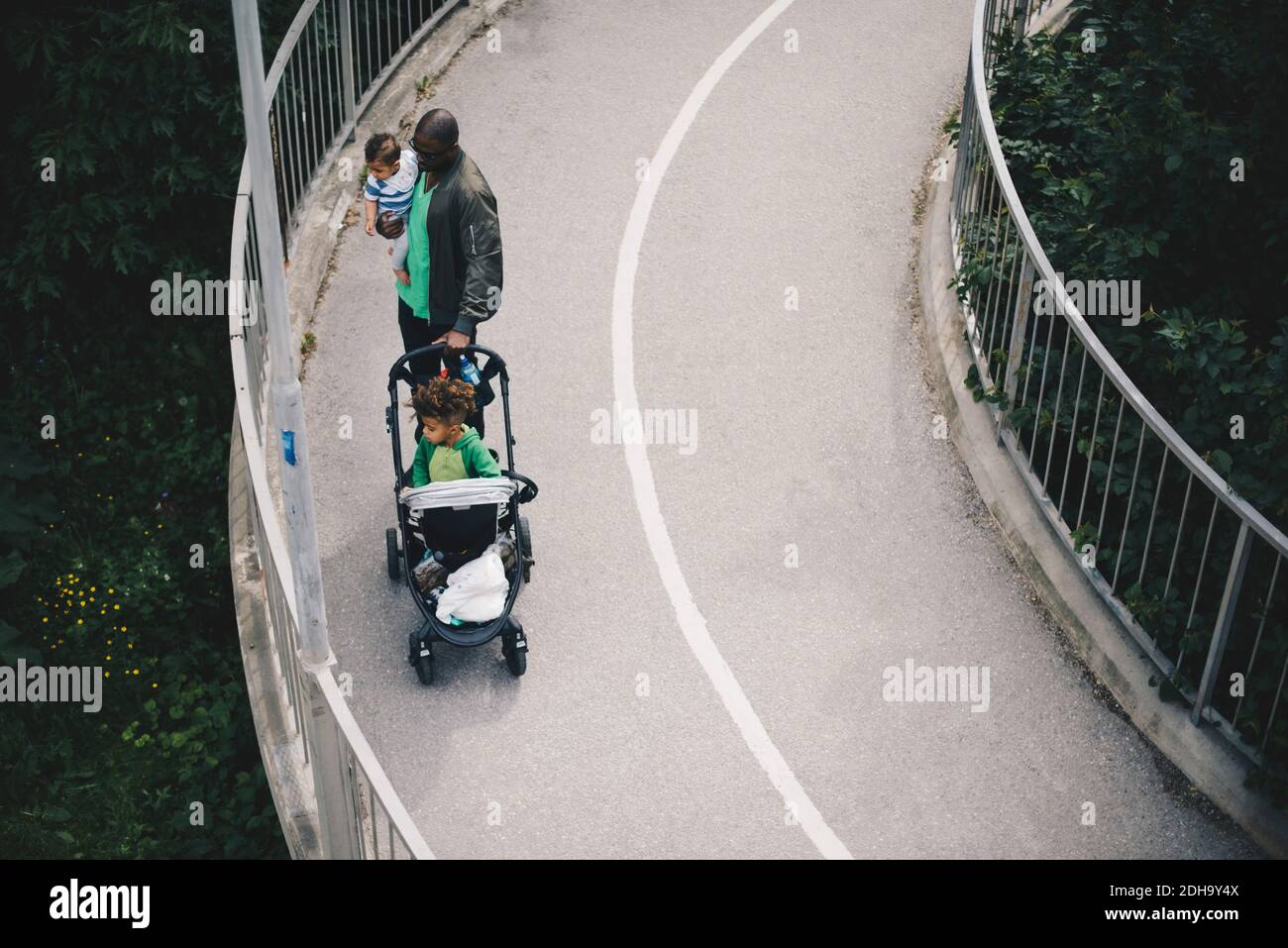 Vista ad alto angolo del padre con i figli in piedi sul ponte su alberi Foto Stock