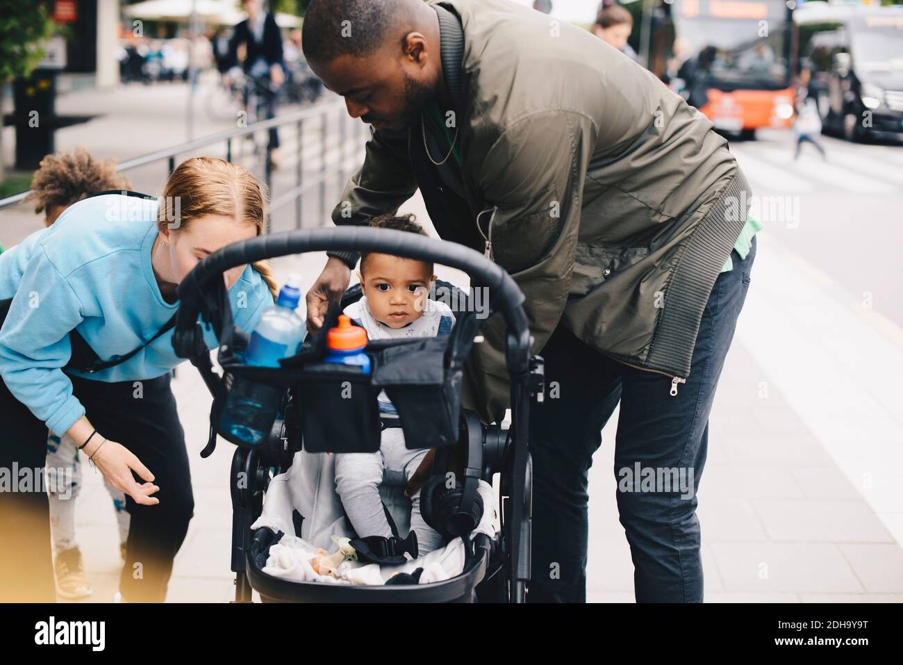 I genitori con il toddler dal passeggino del bambino sul marciapiede in città Foto Stock