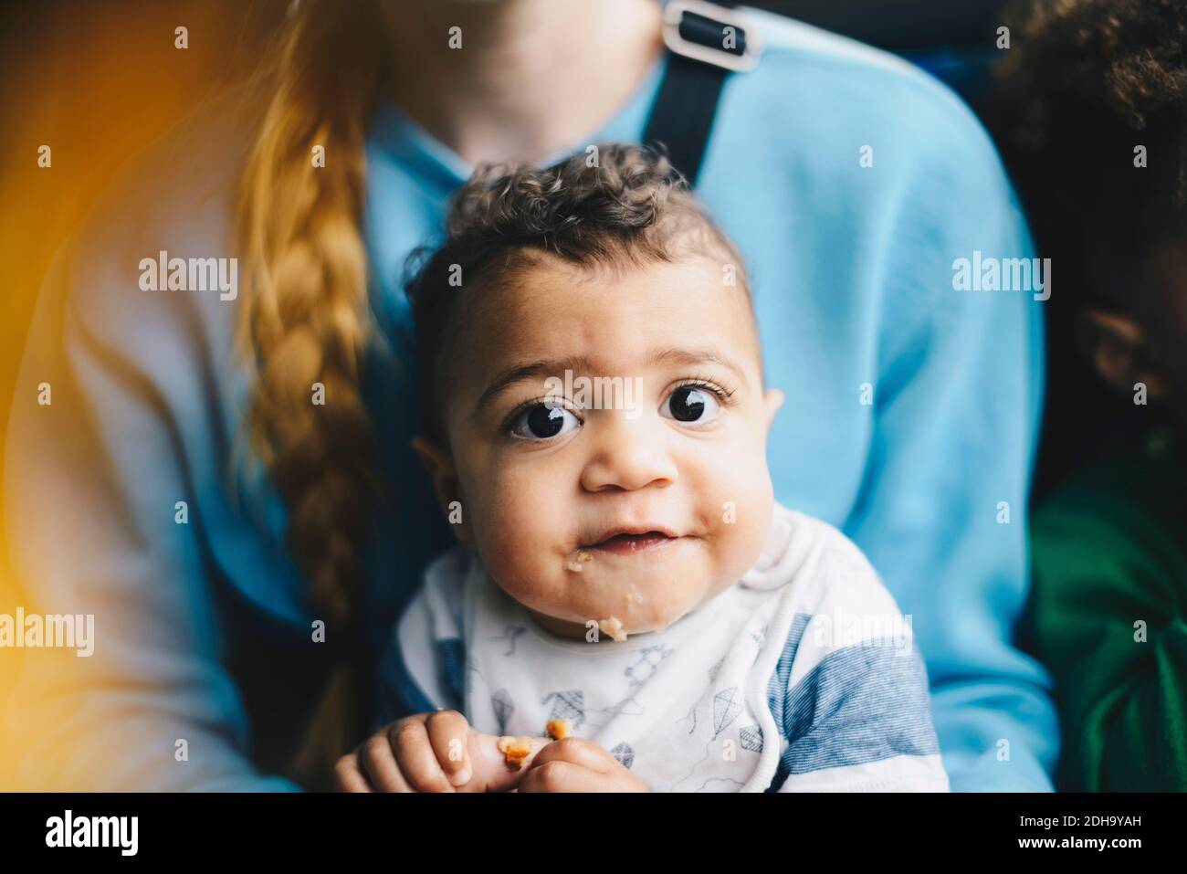 Primo piano del bambino che ha cibo mentre si siede con la madre dentro autobus Foto Stock