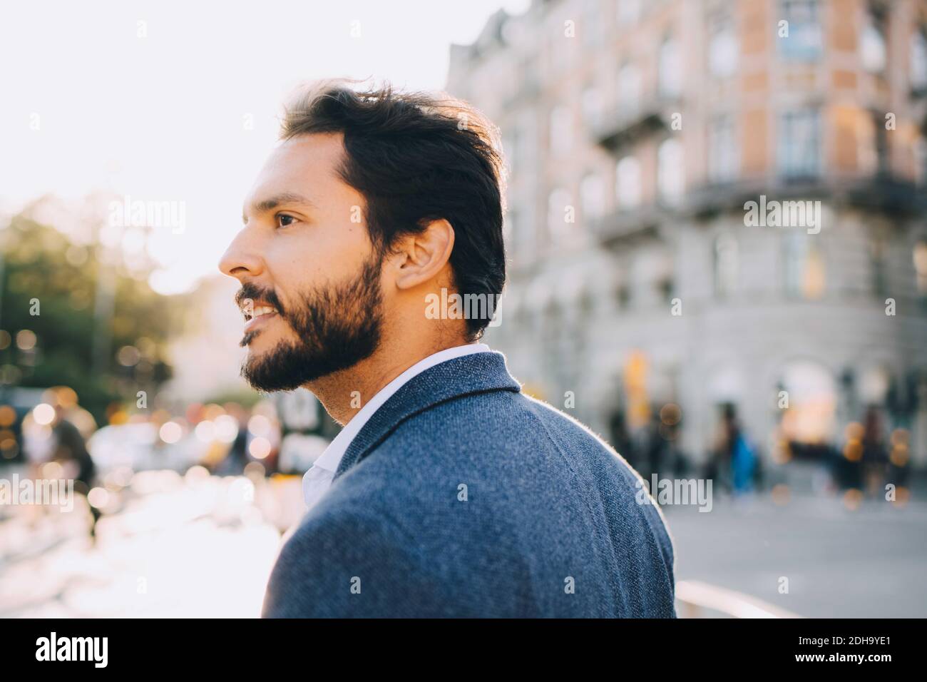 Uomo con barba che guarda lontano durante l'esplorazione della città Foto Stock