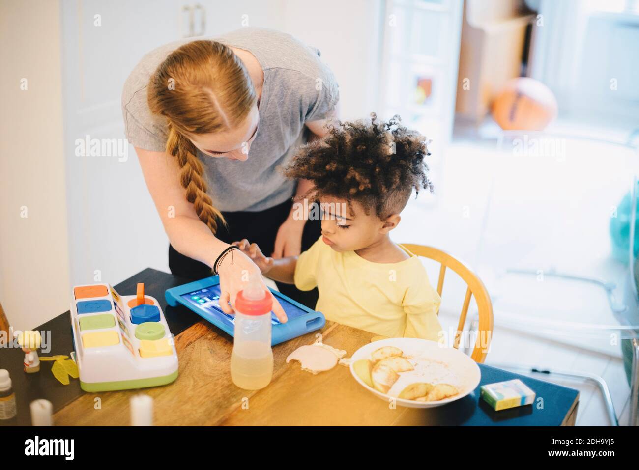 Madre che assiste il figlio nell'uso del tablet digitale a casa Foto Stock