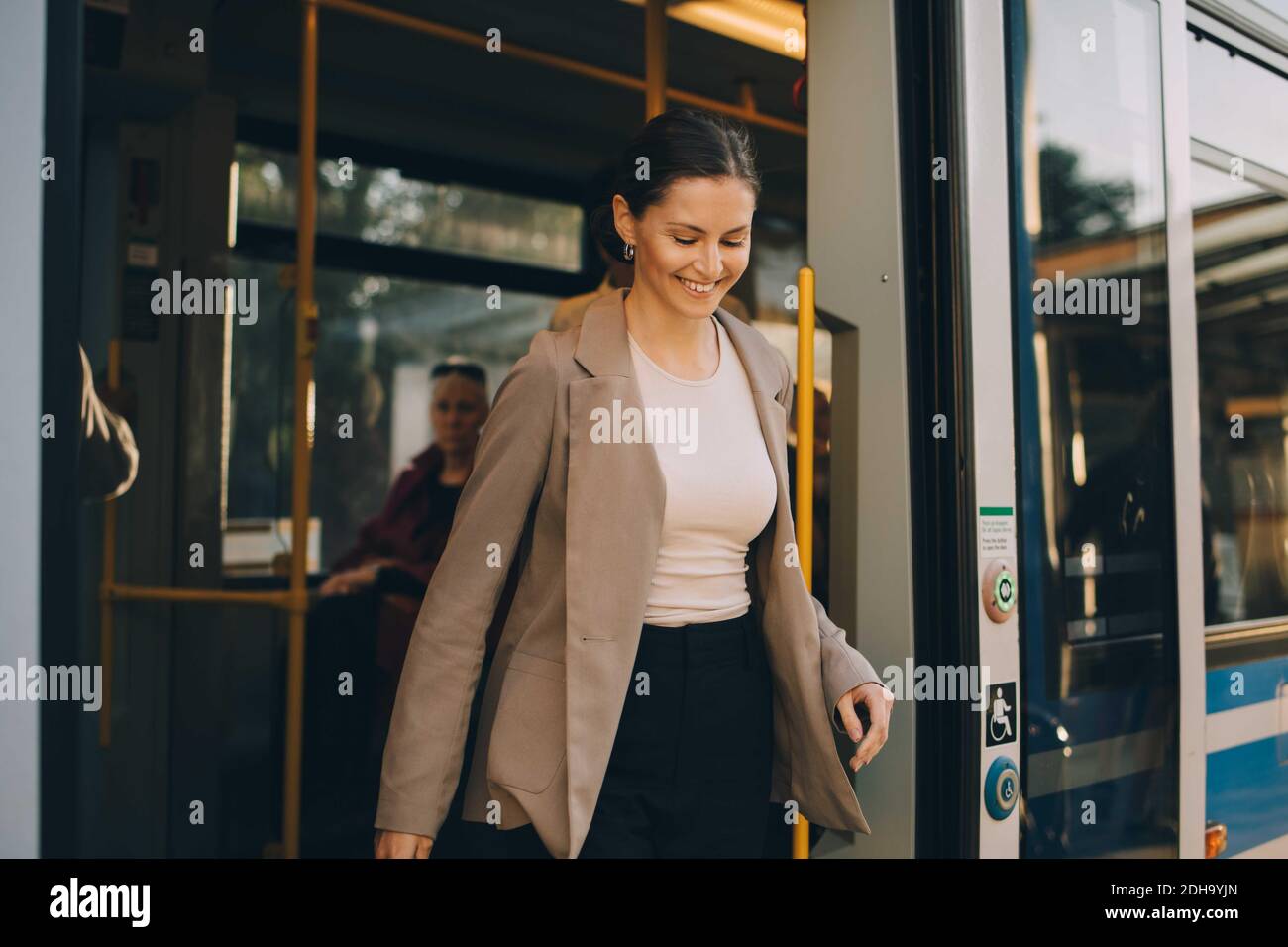 Donna sorridente che esce dal tram durante l'esplorazione della città Foto Stock