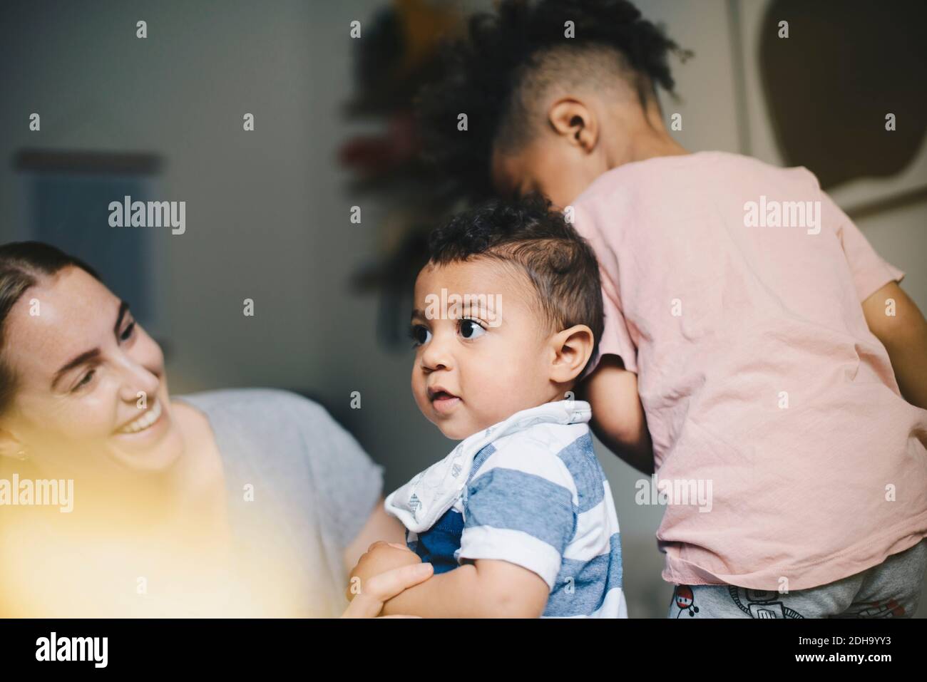 Madre sorridente che gioca con i figli a casa Foto Stock