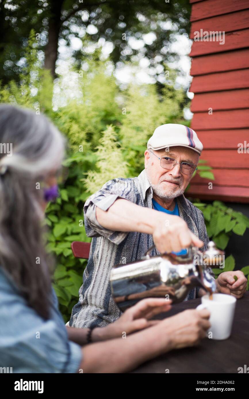 Uomo anziano che guarda la donna mentre versa il caffè in tazza Foto Stock