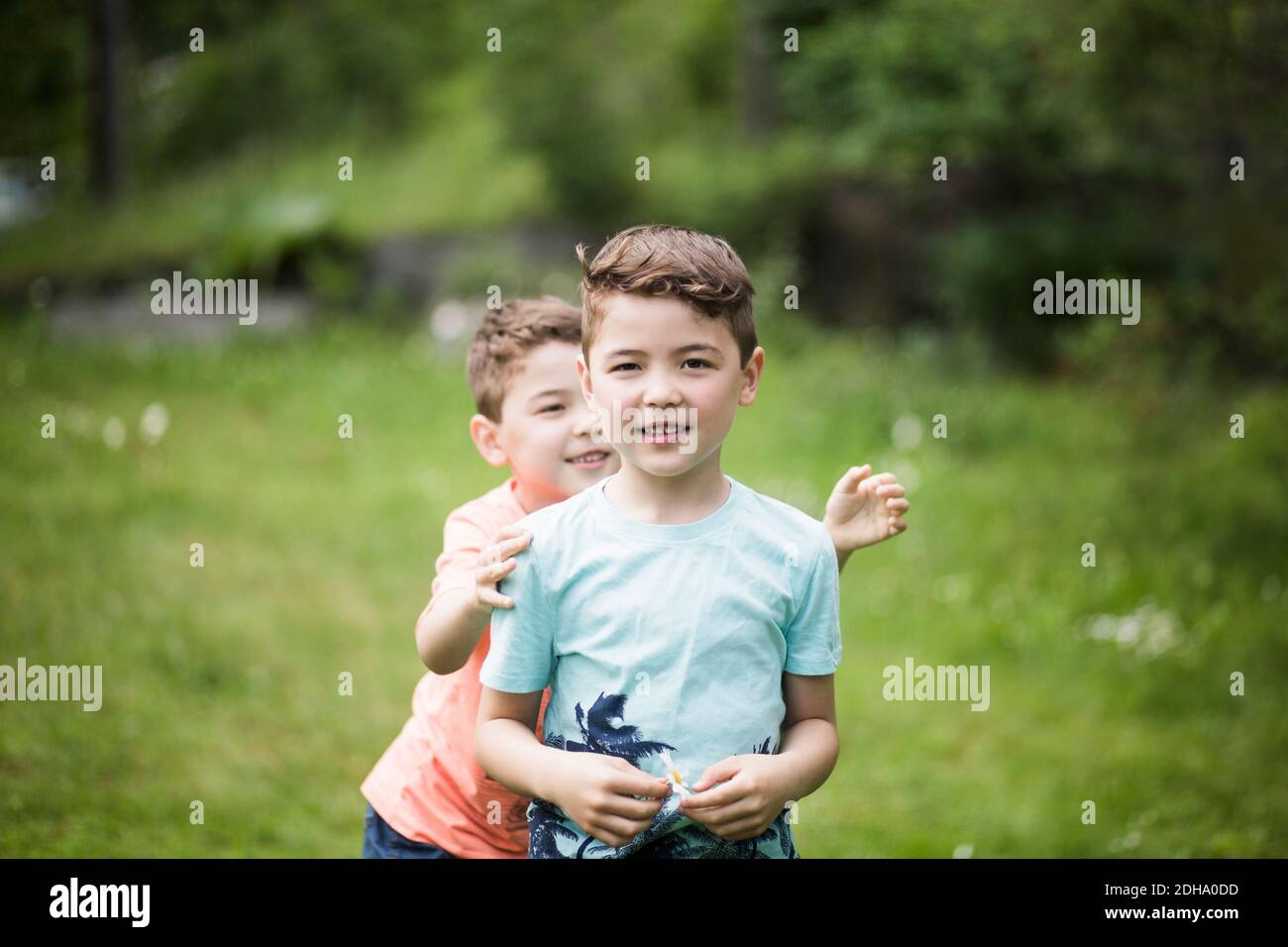 Ritratto di ragazzo con fratello giocoso in piedi nel cortile posteriore Foto Stock