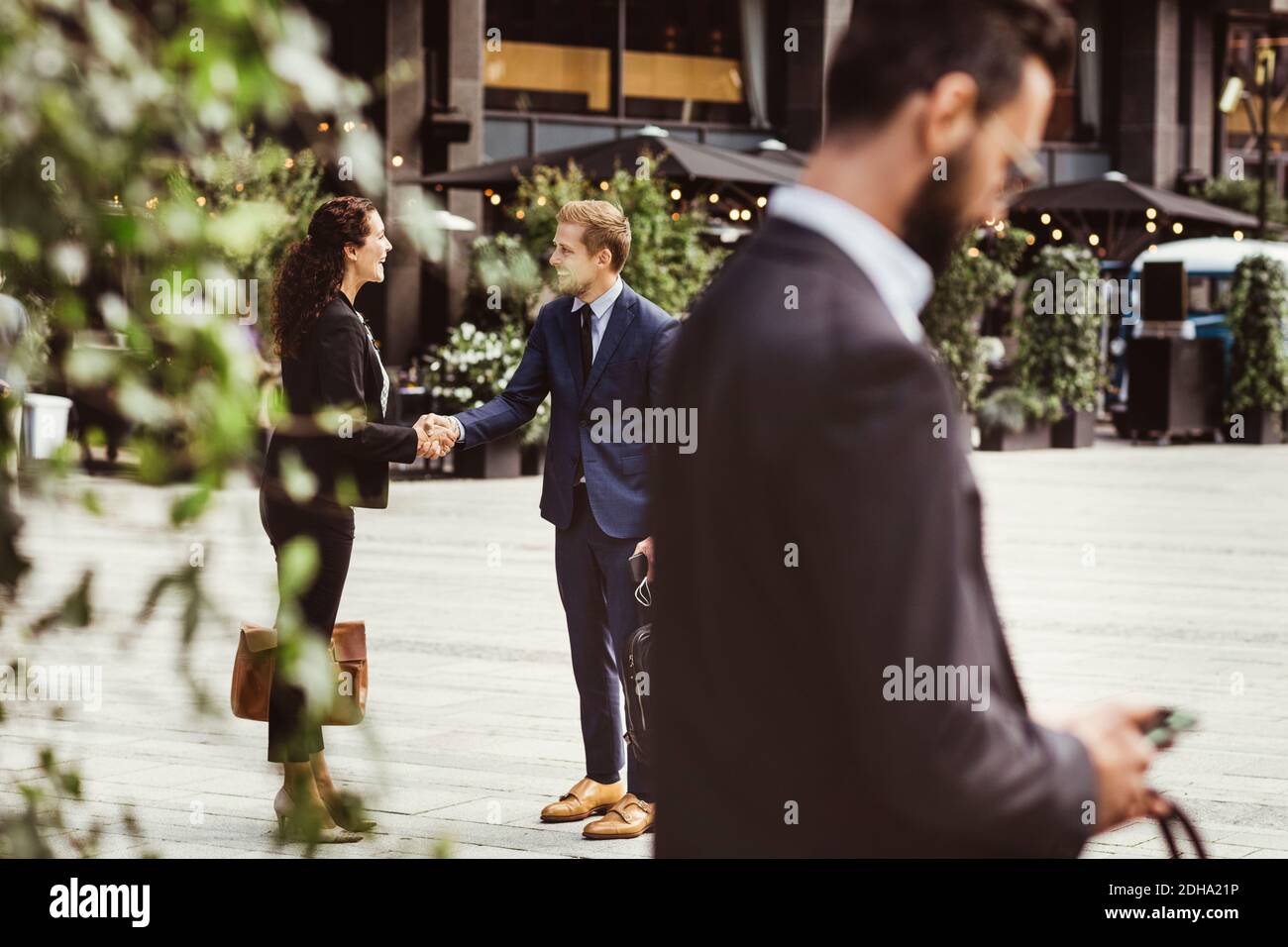Imprenditori maschili e femminili scuotono le mani mentre si levano in piedi all'aperto Foto Stock