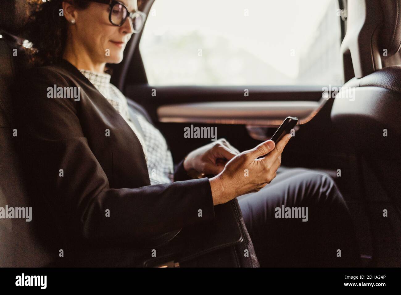 Imprenditore che utilizza il telefono cellulare mentre si siede in auto Foto Stock