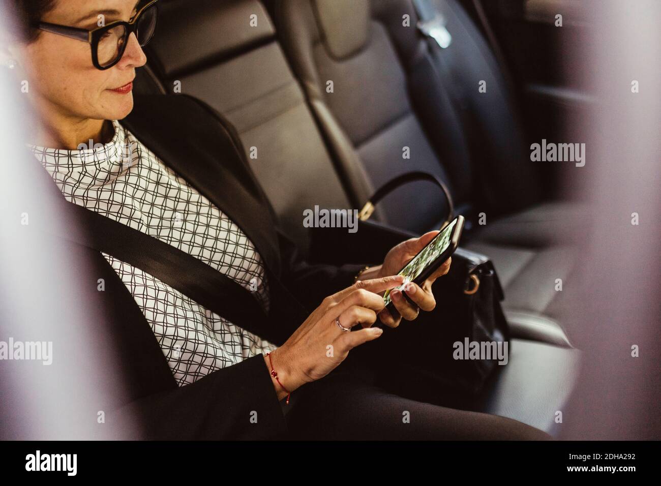 Donna imprenditore che utilizza lo schermo del dispositivo mentre si siede in auto Foto Stock