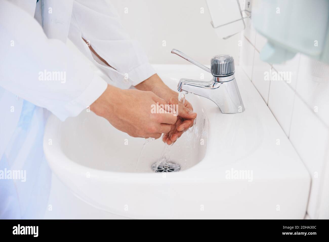 Corto di medico maschile lavando le mani in lavello in ospedale Foto Stock