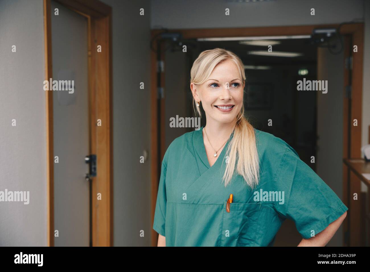 Femmina sorridente per adulti di media altezza in piedi nel corridoio dell'ospedale Foto Stock