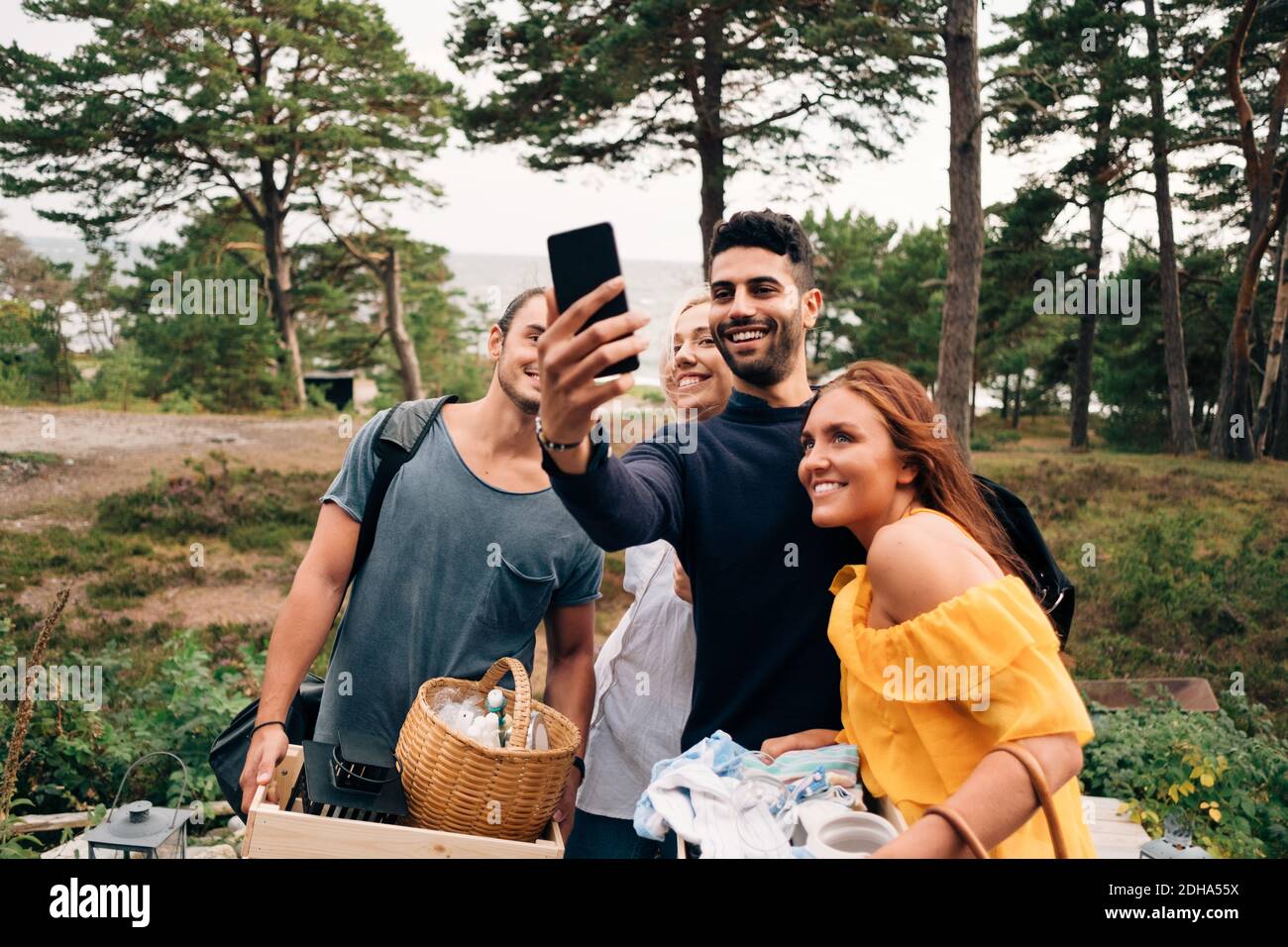 Felici amici di sesso maschile e femminile che prendono selfie dallo smartphone in foresta Foto Stock