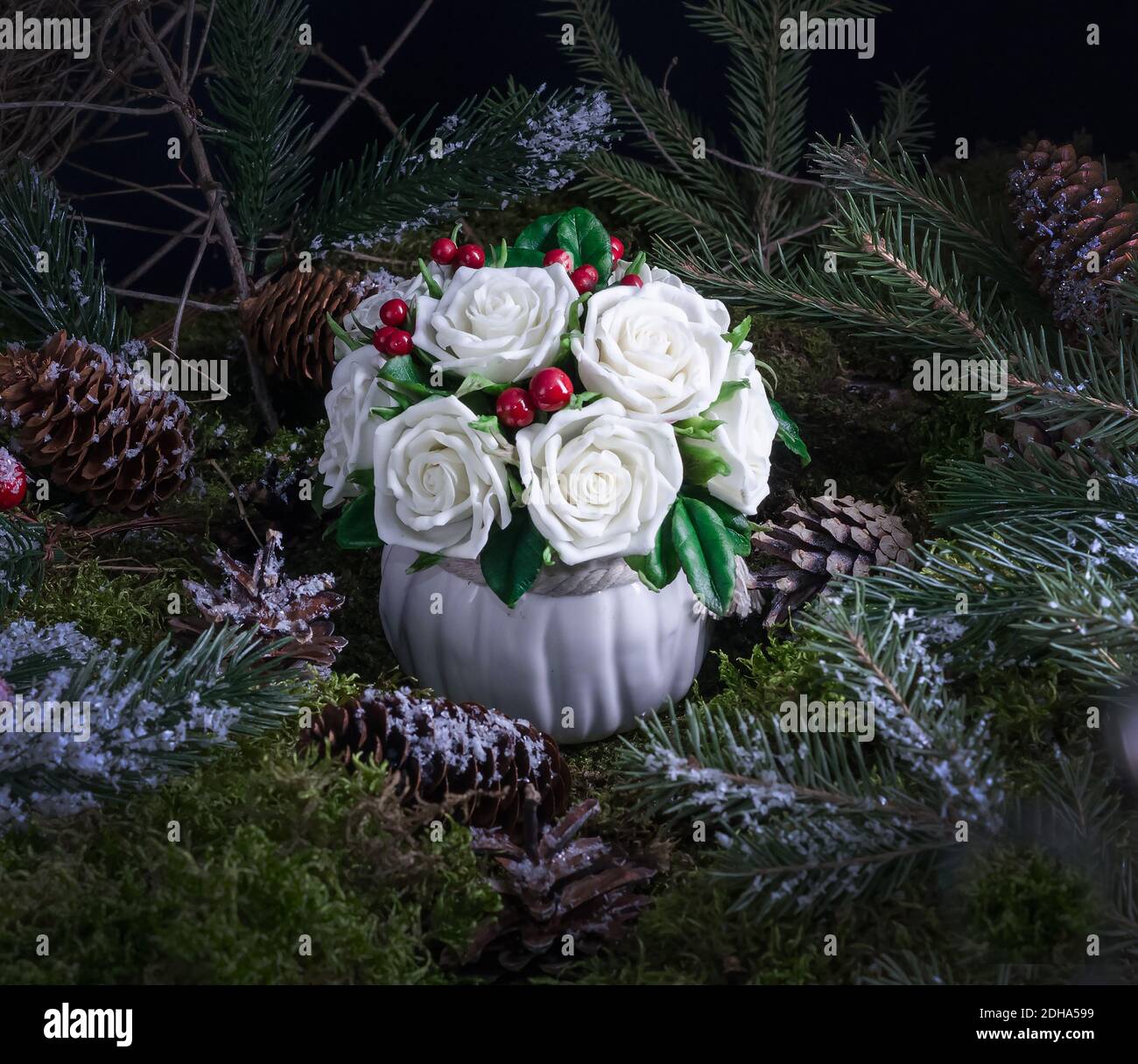 Decorazione casa di Natale composizione di rose bianche e bacche su uno sfondo naturale muschio, idea di decorazione casa Foto Stock