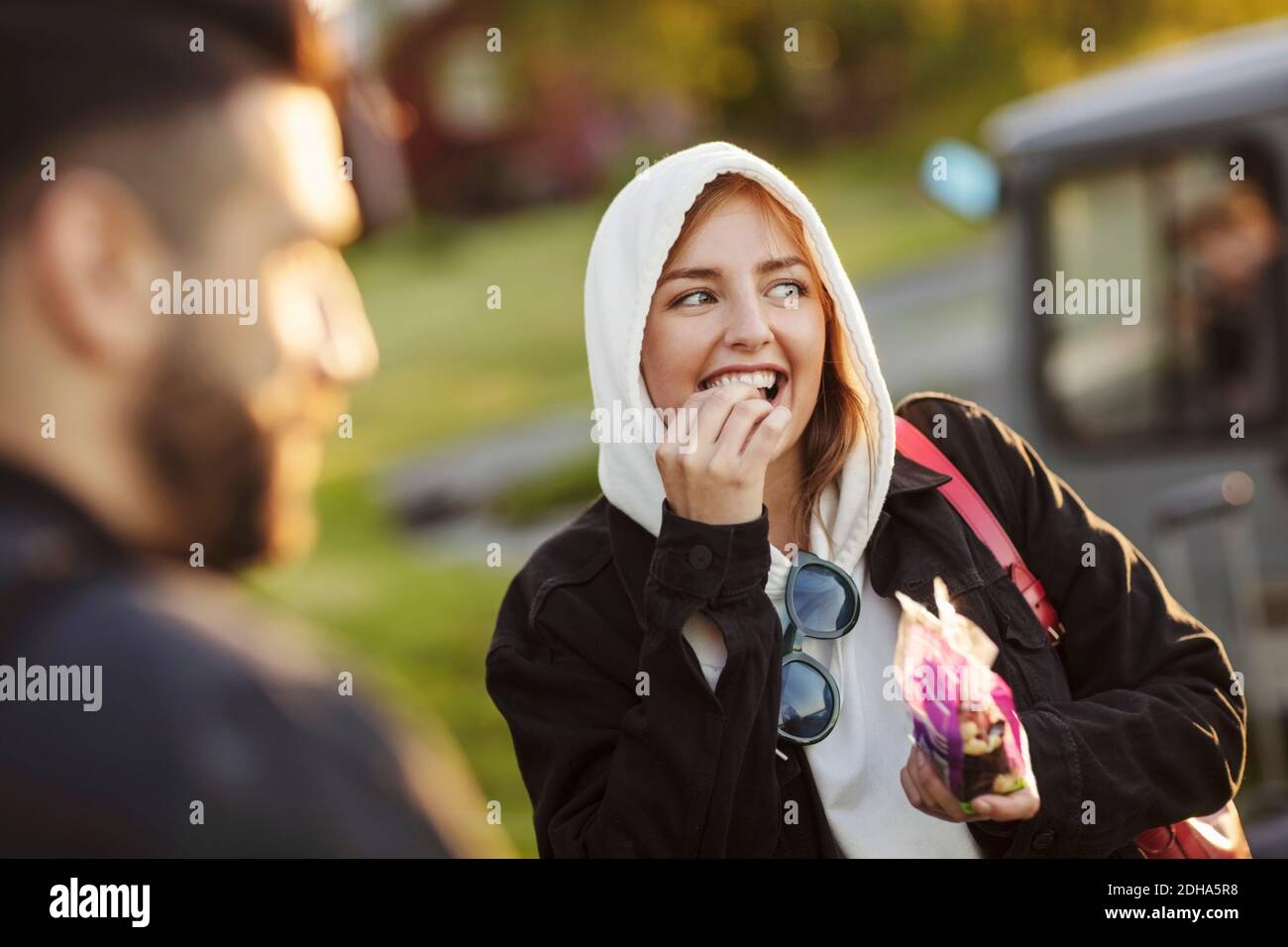 Giovane donna allegra che mangia dall'uomo mentre si guarda via Foto Stock
