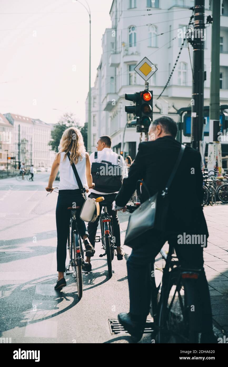Tutta la lunghezza dei colleghi di affari che cavalcano in bicicletta sulla strada dentro città Foto Stock