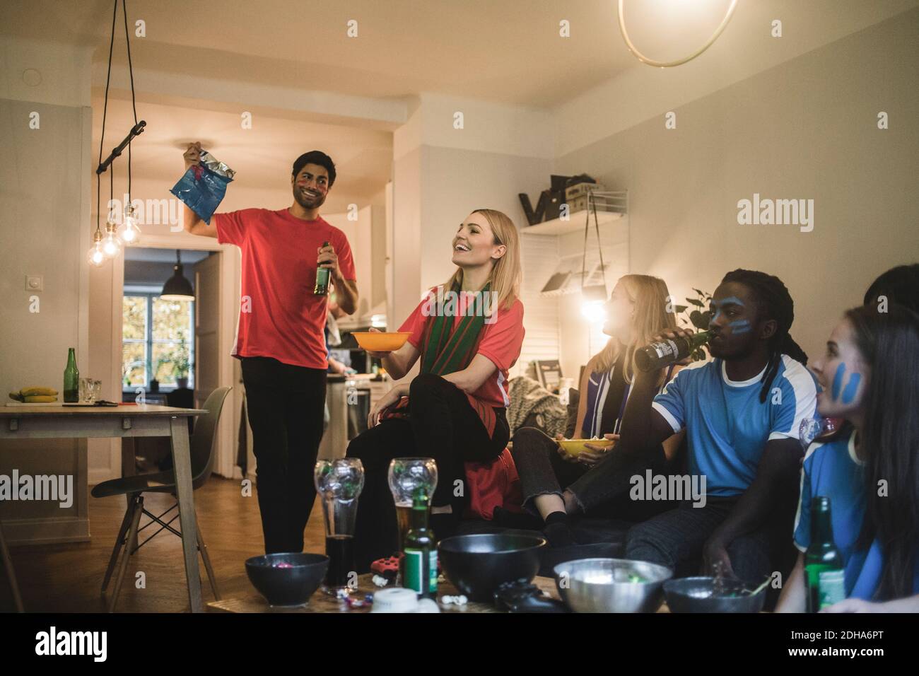 Sorridendo amici di sesso maschile e femminile guardando partita di calcio in vita camera Foto Stock