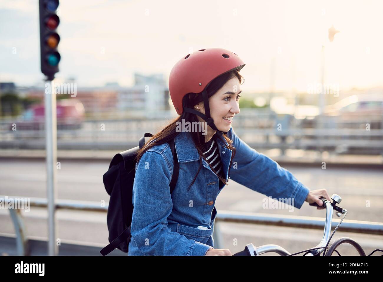 Sorridente donna mid adulta in bicicletta in città Foto Stock