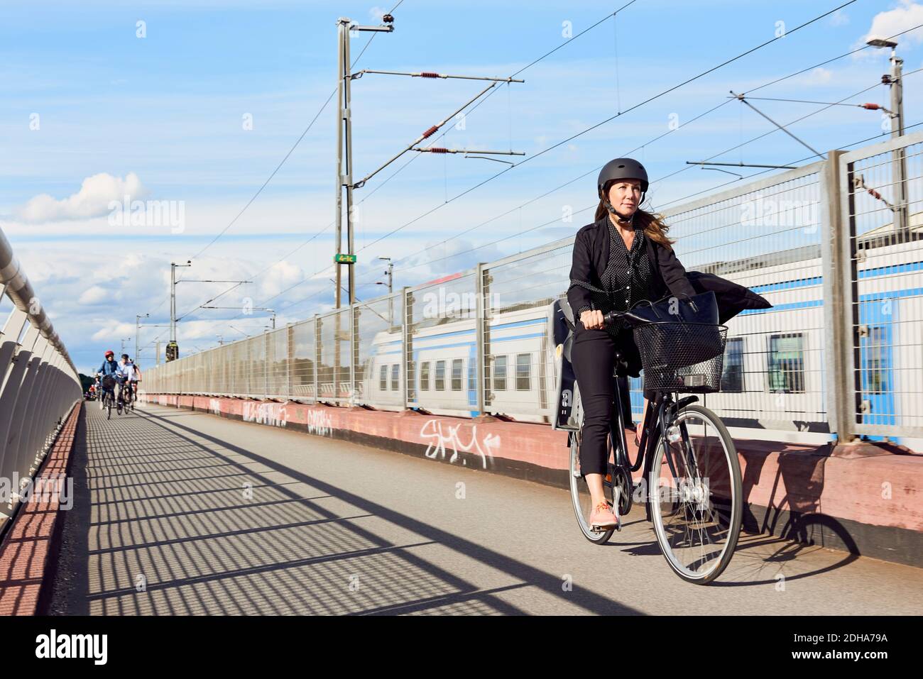Donna matura in bicicletta su strada da recinzione contro il cielo Foto Stock