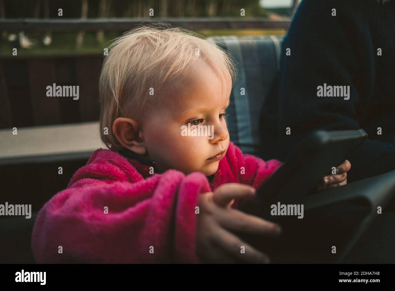 Primo piano di una ragazza che tiene un tablet digitale mentre si siede da madre Foto Stock