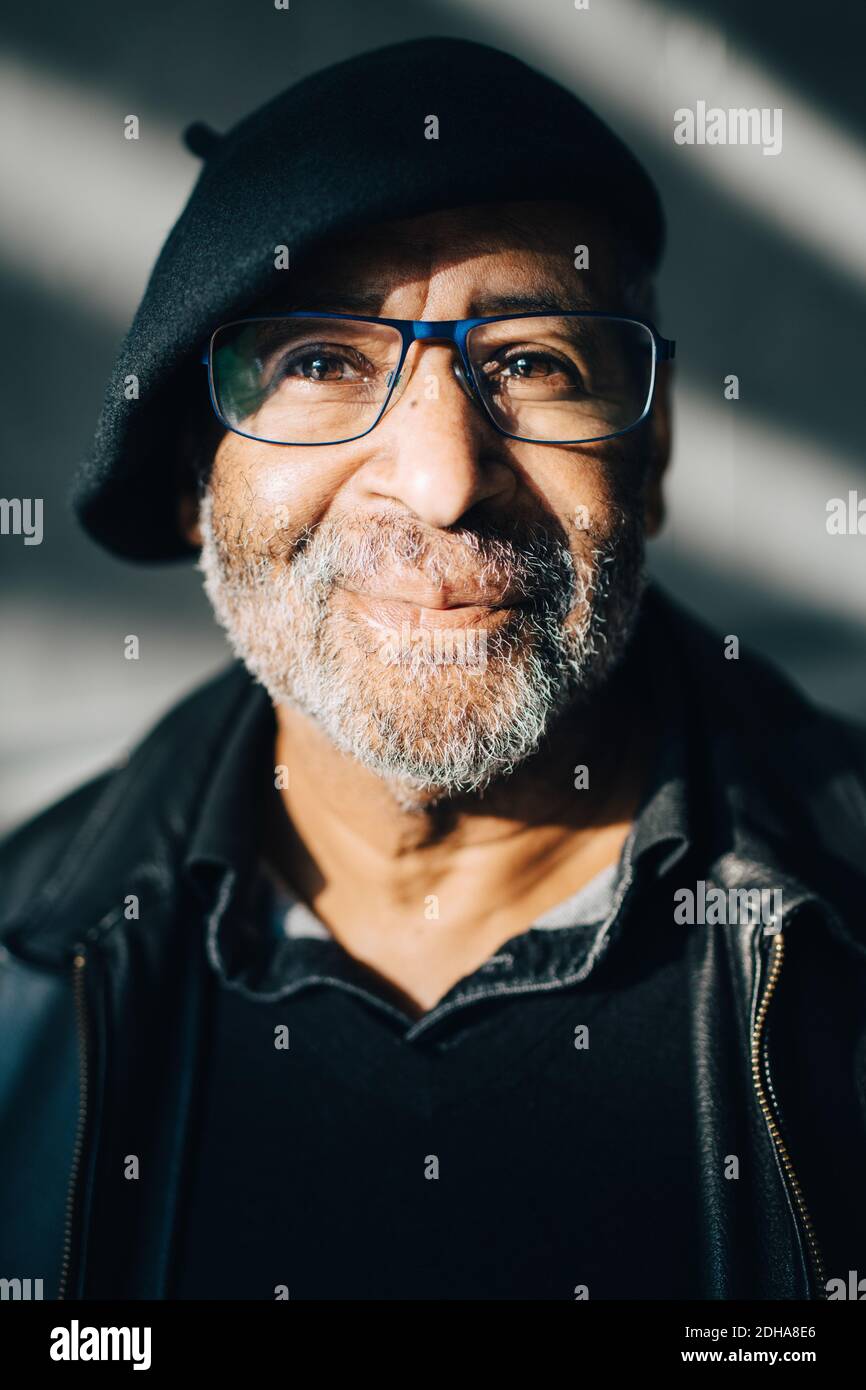 Ritratto di sorridente anziano con occhiali contro muro Foto Stock