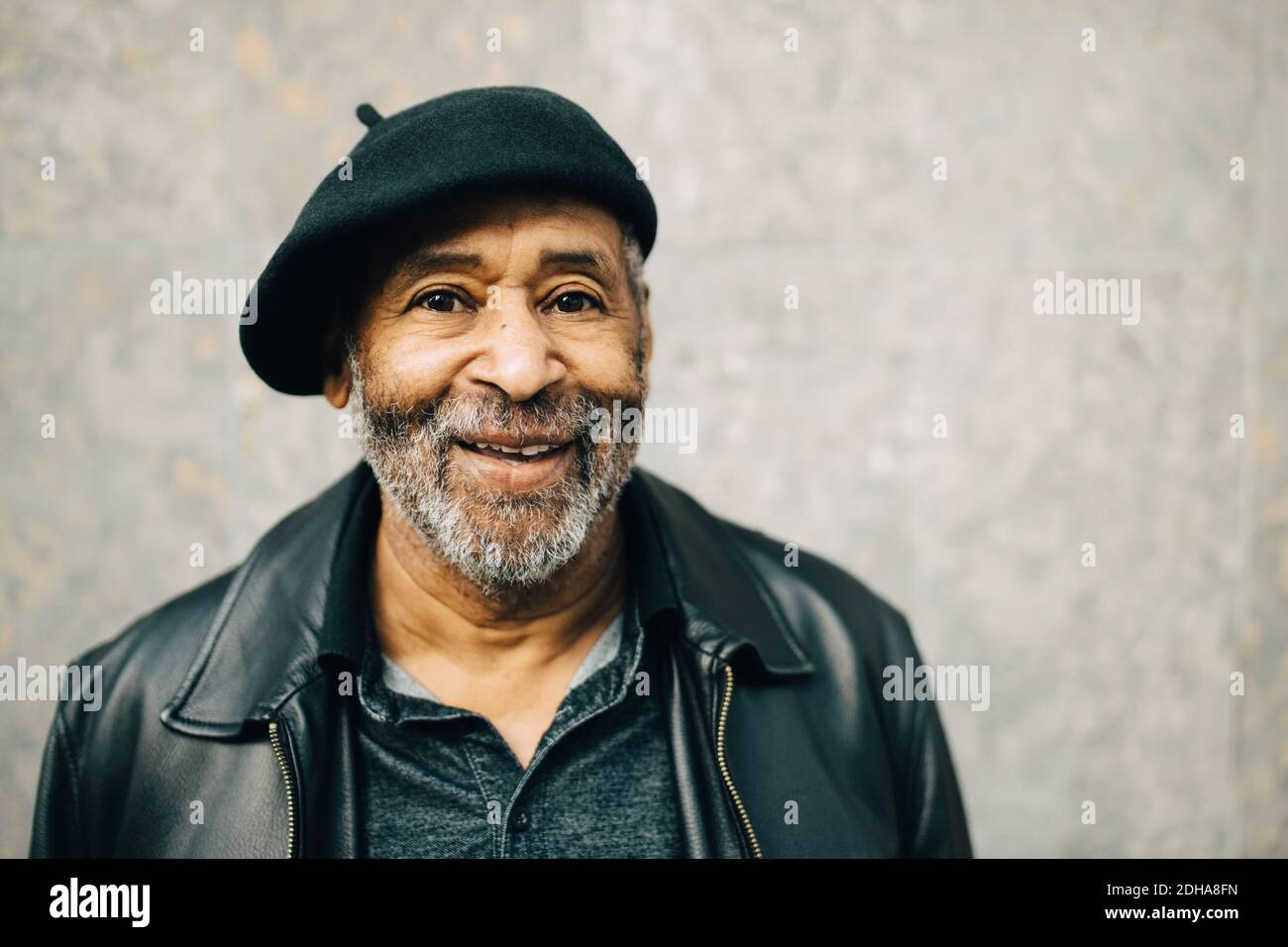Ritratto di sorridente uomo anziano contro muro Foto Stock
