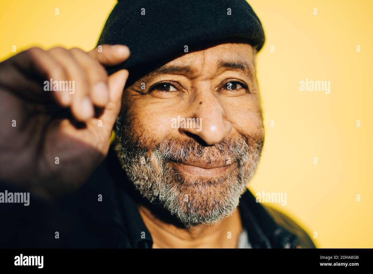 Uomo anziano sorridente su sfondo giallo Foto Stock