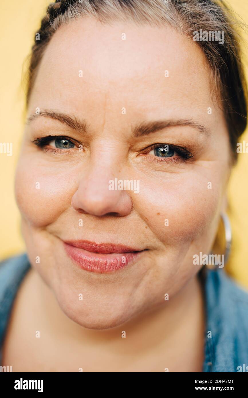 Primo piano ritratto di donna sorridente su sfondo giallo Foto Stock
