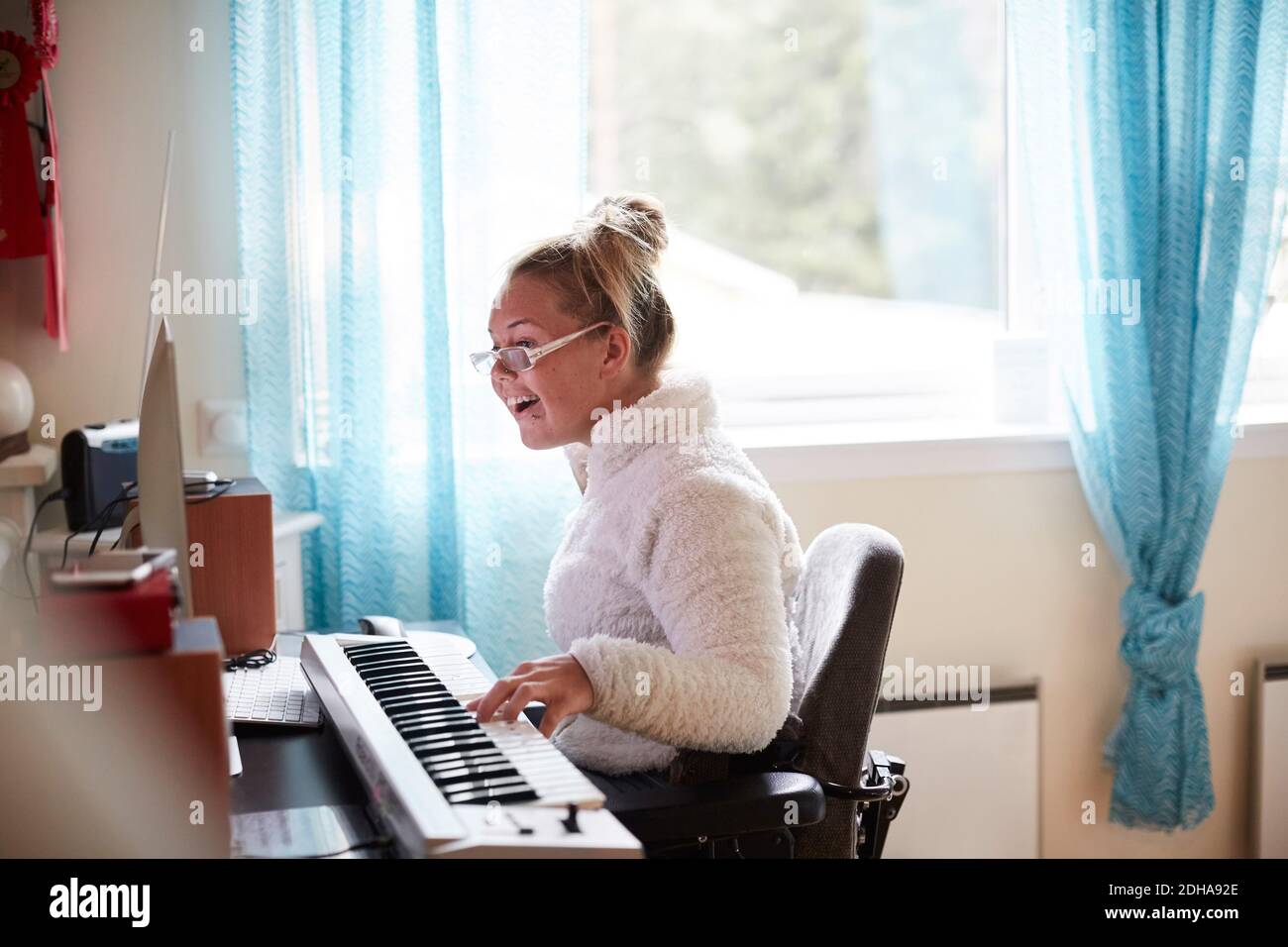 Giovane donna disabile che suona piano a casa Foto Stock