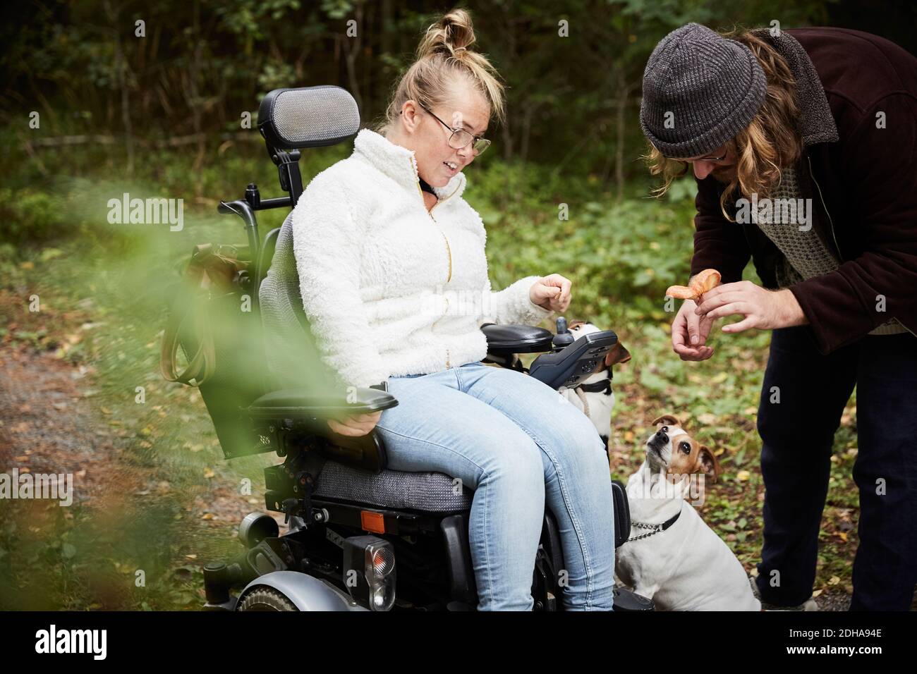 Donna disabile in sedia a rotelle che guarda il custode che tiene il fungo dentro foresta Foto Stock