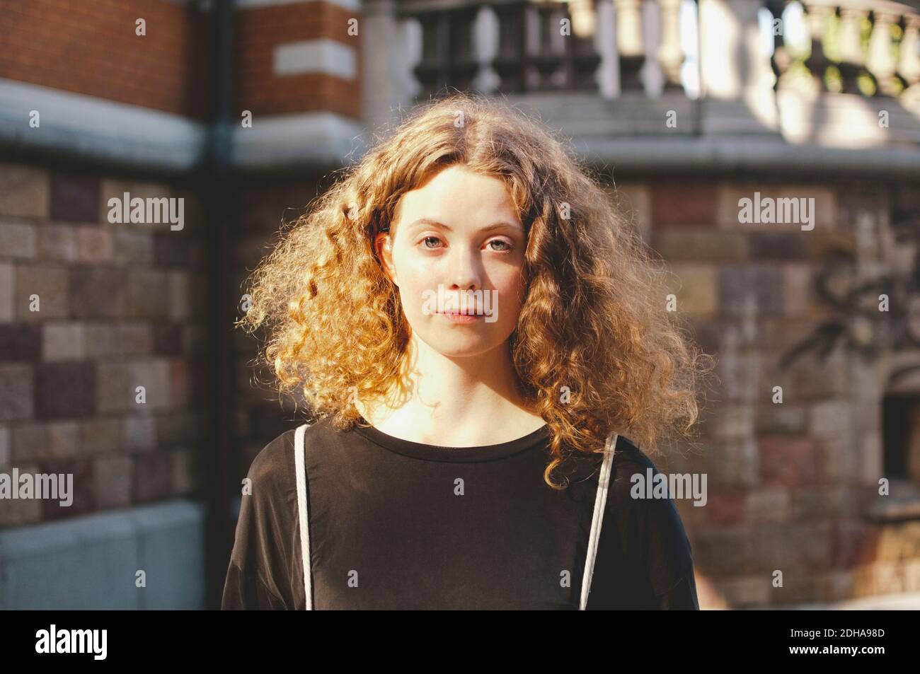 Ritratto di giovane studentessa con capelli marroni in piedi fuori università Foto Stock