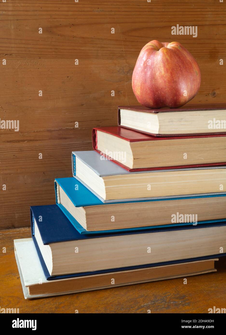 La mela rossa con il libro poggia su reggimento di legno. I soggetti in primo piano. Foto Stock