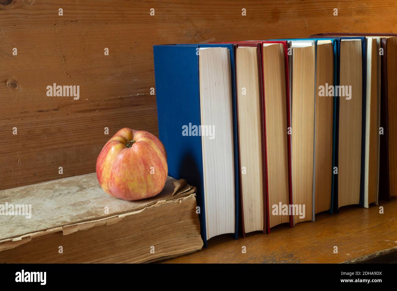 La mela rossa con il libro poggia su reggimento di legno. I soggetti in primo piano. Foto Stock