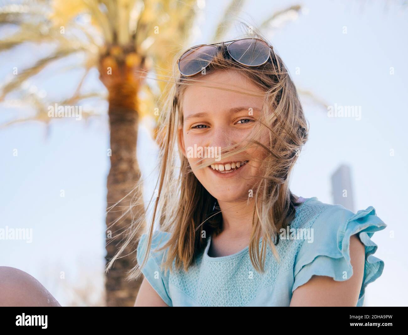 Ritratto di ragazza sorridente seduta contro il cielo Foto Stock