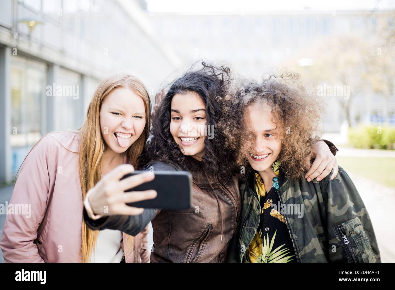 Felice ragazza adolescente che prende selfie con gli amici da smartphone Foto Stock