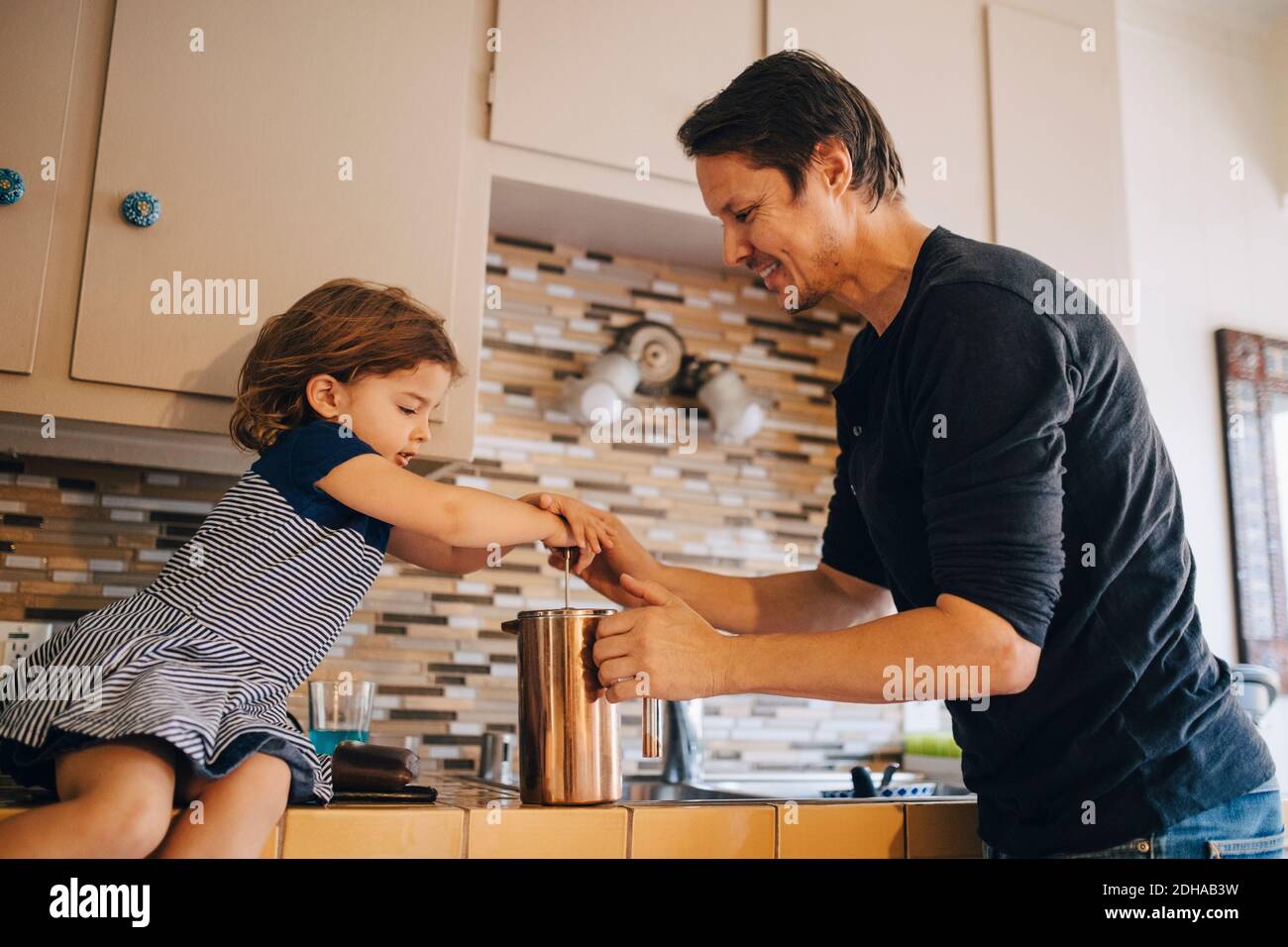 Padre e figlia maturi che lavorano con la macchina da caffè francese in cucina Foto Stock