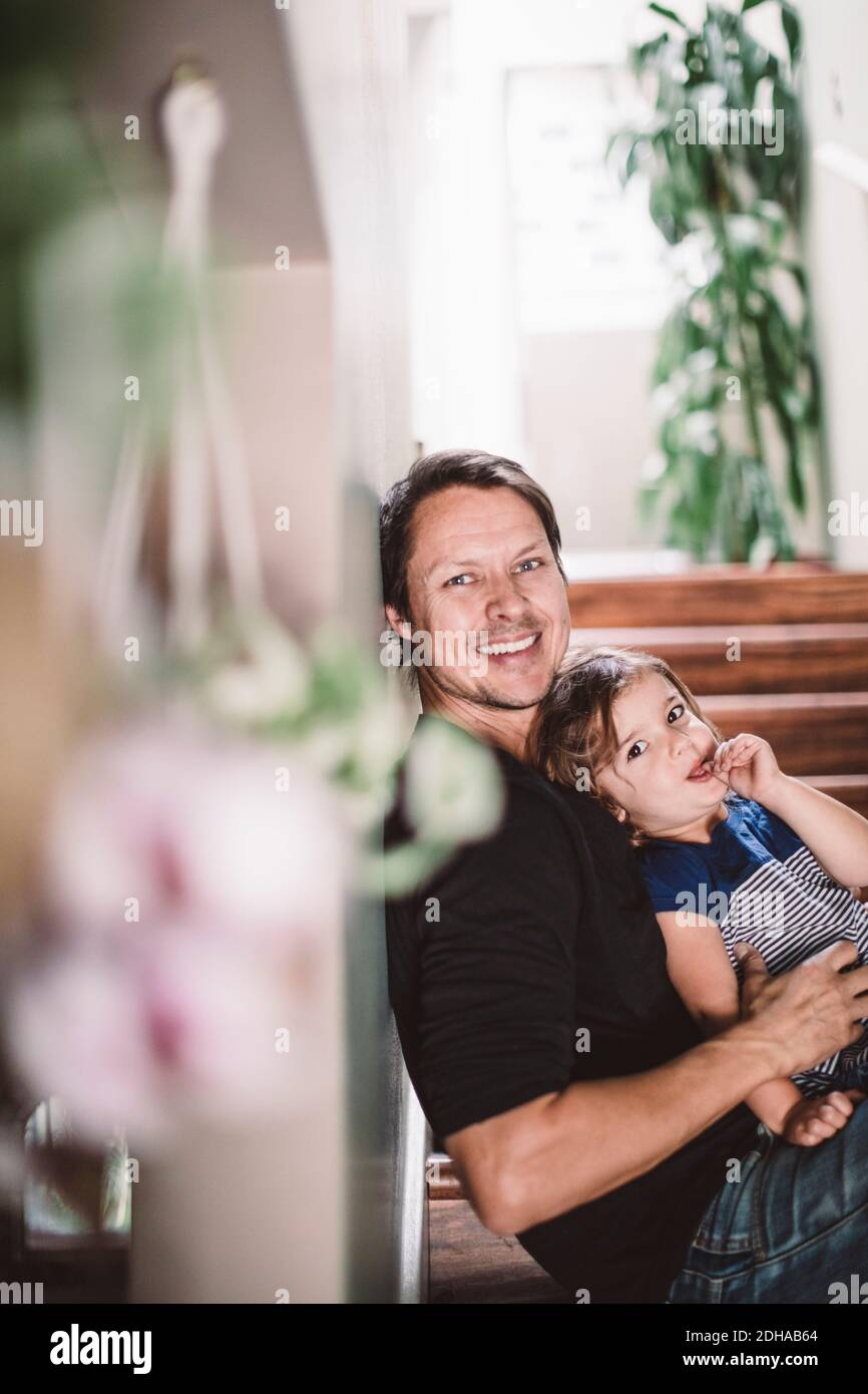 Ritratto di felice padre con figlia seduta sui gradini a. casa Foto Stock