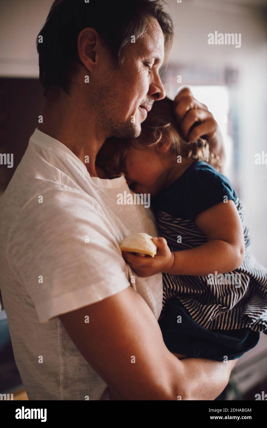Padre maturo con gli occhi chiusi tenendo la figlia in braccio Foto Stock