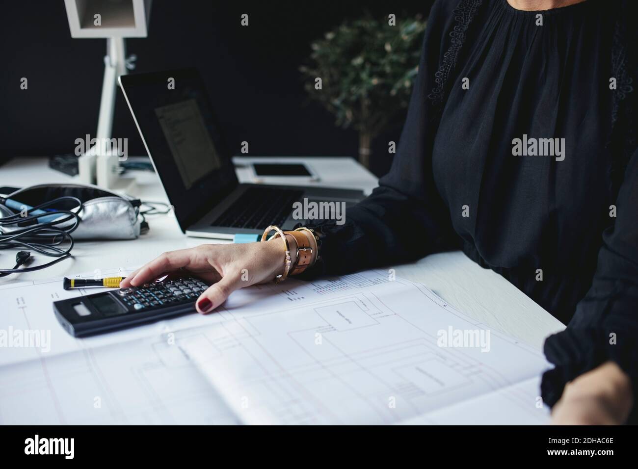 Sezione centrale di un ingegnere femminile con un progetto sulla scrivania a casa ufficio Foto Stock