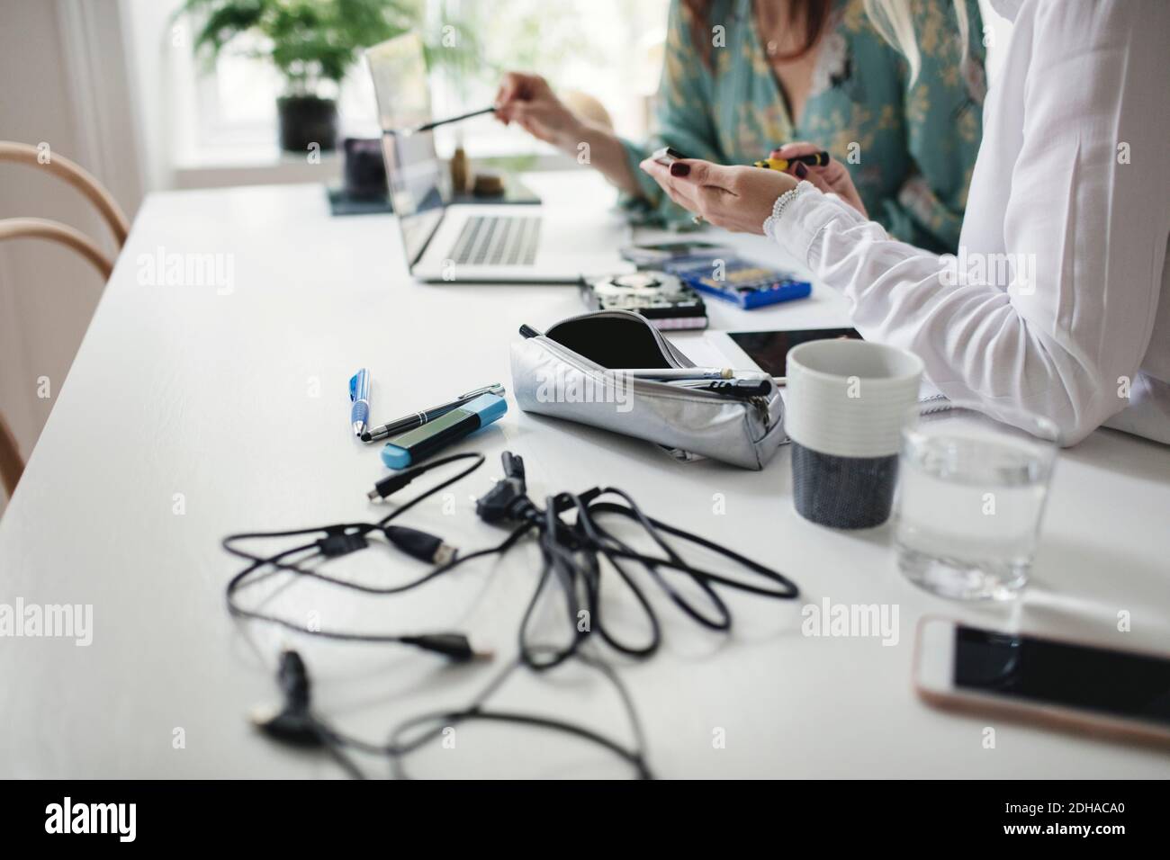 Sezione centrale di colleghi che lavorano sul disco rigido al tavolo in ufficio a casa Foto Stock