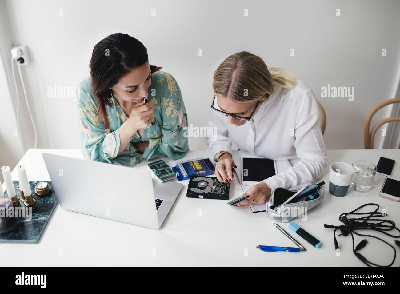Visualizzazione ad angolo elevato di ingegneri femminili che lavorano su disco rigido a tavola in ufficio domestico Foto Stock