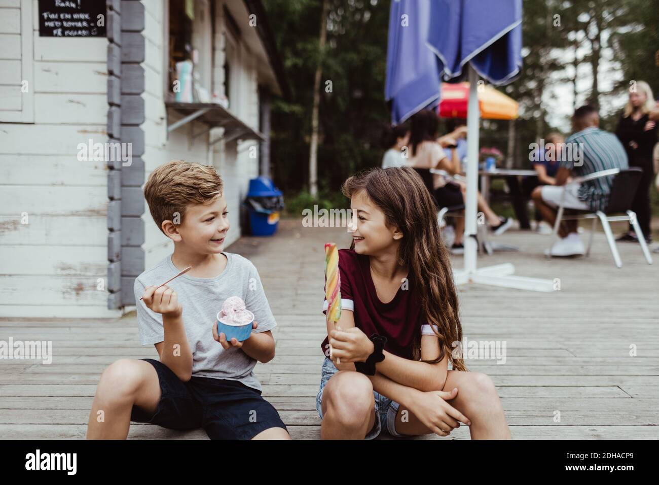 Sorridi fratello e sorella che mangiano cibo dolce mentre si siedono pavimento in legno Foto Stock