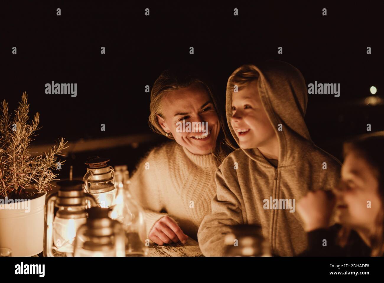 Madre sorridente che guarda i bambini mentre si siede al tavolo ristorante Foto Stock