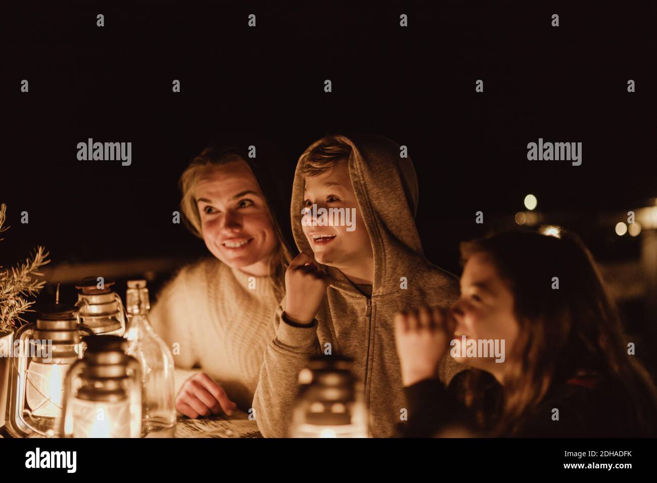 Madre sorridente seduta con i bambini al ristorante di notte Foto Stock