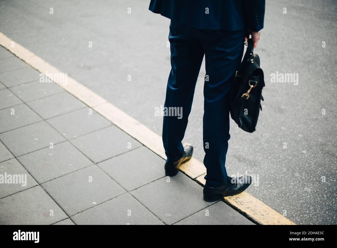 Sezione bassa di uomo d'affari maturo con borsa in piedi sul marciapiede in città Foto Stock