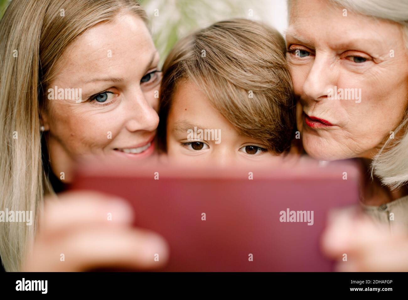 Primo piano di una famiglia di più generazioni che prende selfie nel telefono cellulare Foto Stock