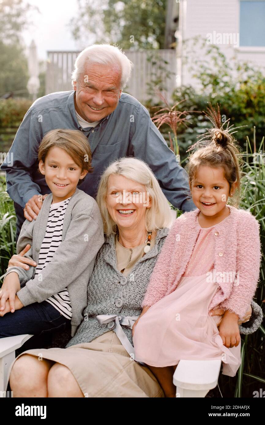 Ritratto di nonni e nipoti seduti in cortile Foto Stock