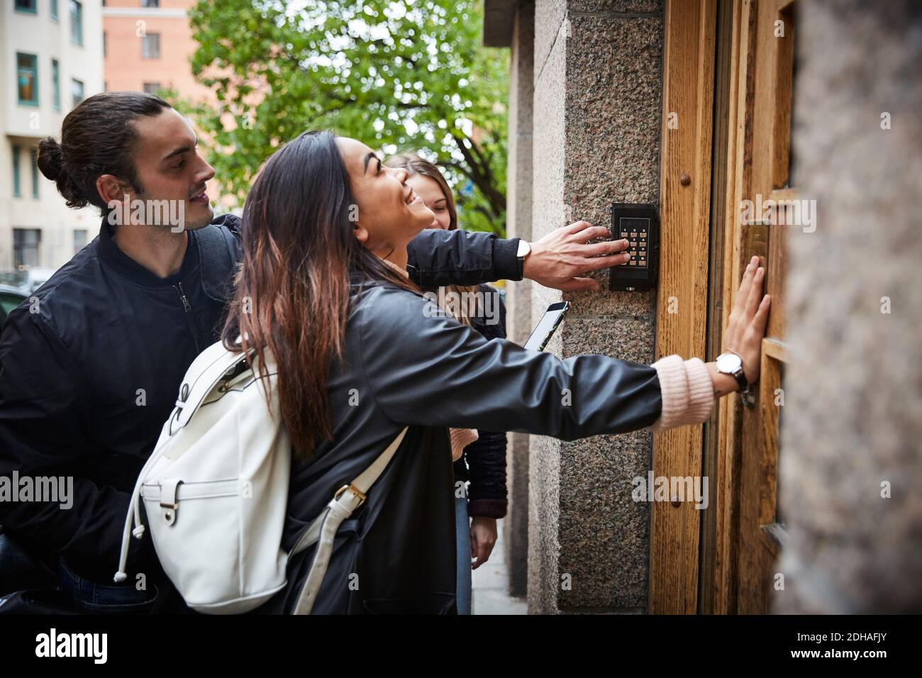 Uomo con amici di sesso femminile che immettono il codice alla serratura della porta città Foto Stock