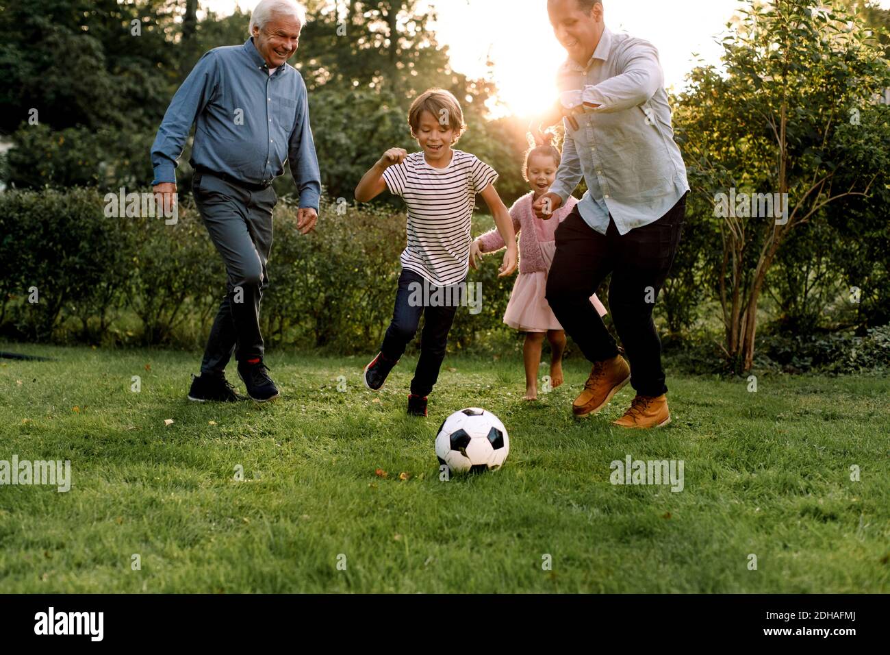 Tutta la famiglia di più generazioni che gioca a calcio in cortile Foto Stock