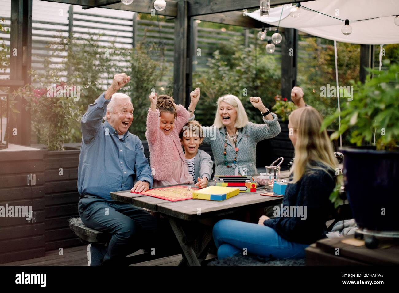 Allegro gioco da tavolo con la famiglia mentre si siede al tavolo cortile Foto Stock