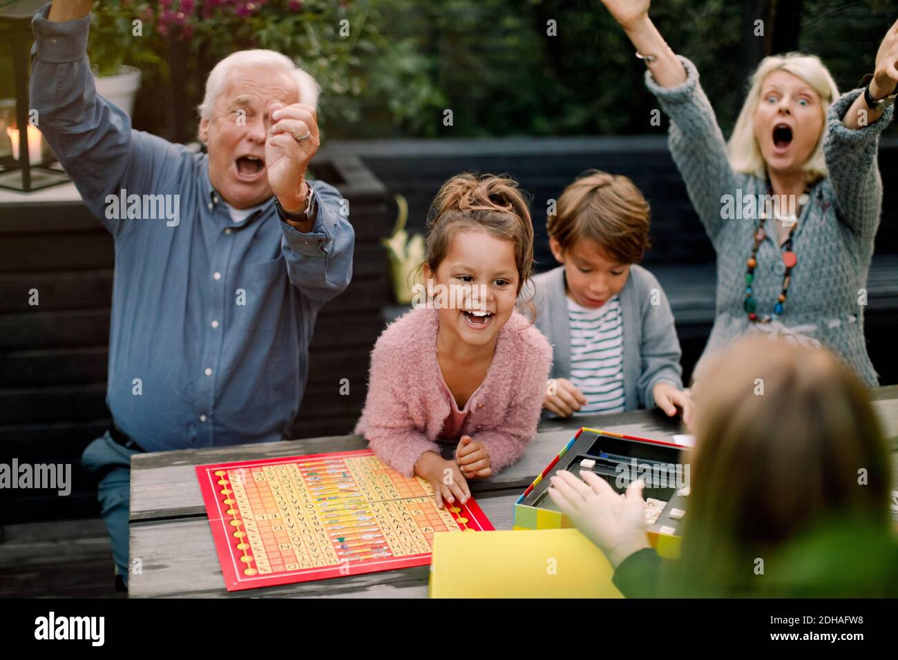 Sorridente allegro gioco da tavolo con la famiglia seduto al tavolo in cortile Foto Stock